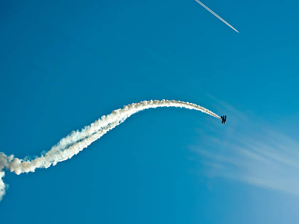 Plane in airshow Aerobatic biplane flying with smoke against blue sky, low angle view stunt airplane airshow air vehicle stock pictures, royalty-free photos & images