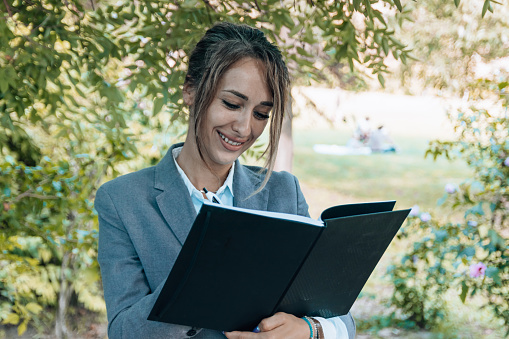 This image captures a moment of thoughtful reflection as a businesswoman holds a notebook while comfortably seated on a bench