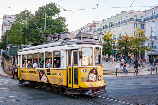 Lisbon, Portugal - September 21, 2022: Famous vintage yellow tram 28 in street at the crowded Luis De Camoes square Praca Luis de Camoes, one of the biggest squares in Lisbon city in Portugal