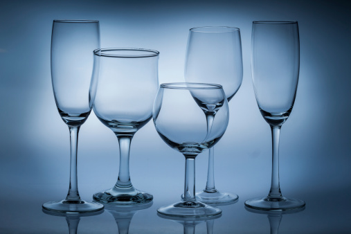 Different types of empty glasses on a blue background.
