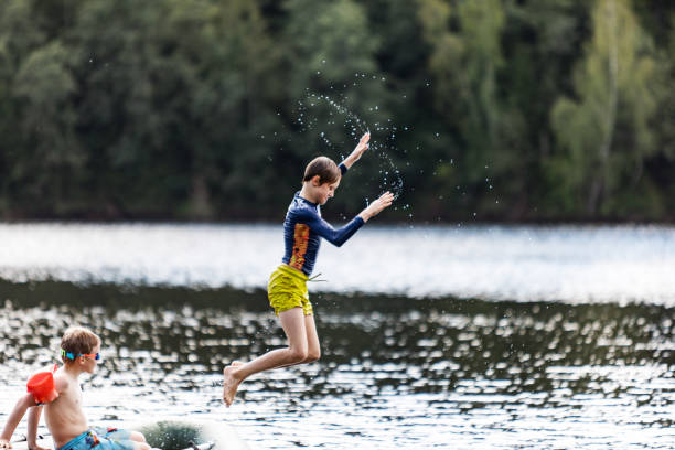 niños saltando y buceando desde un bote inflable en el lago. - child inflatable raft lake family fotografías e imágenes de stock