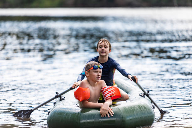 garçons sculling bateau pneumatique - child inflatable raft lake family photos et images de collection