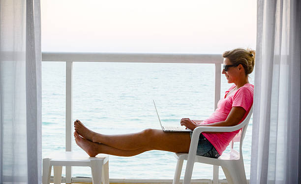 istock Woman using laptop on a balcony with ocean view 161947284