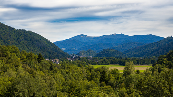 A small village on the slope of a high hill and the edge of a forest. Altai, Siberia, Russia.