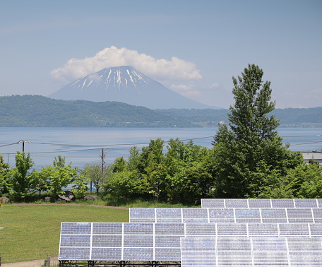 Foreground shows solar panels near Lake Toya. Mount Yotei stands in the background. Spring morning in Hokkaido.