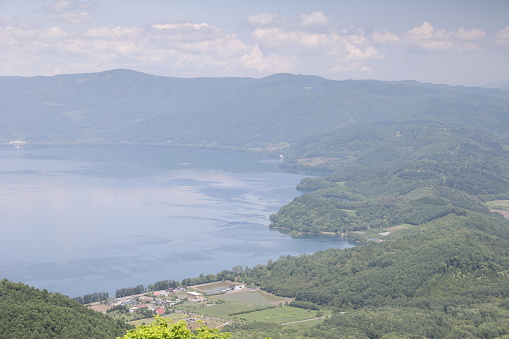 The volcanic landscape viewed from Mount Usu in Sobetsu. Lake Toya is a caldera lake rimmed with dense forests. Spring afternoon in Usu District.