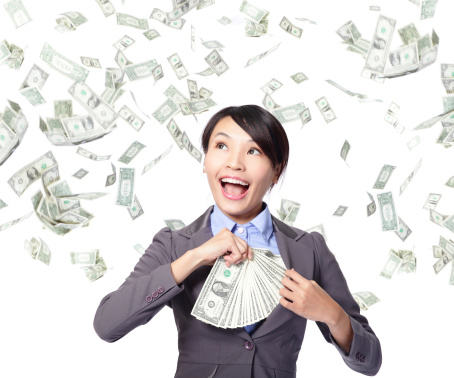 happy business woman with earned dollar bills us money in suit pocket under a money rain - isolated over a white background, asian beauty model
