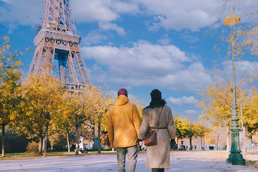 Couple walking next to Eiffel Tower in Paris, winter or autumn season December