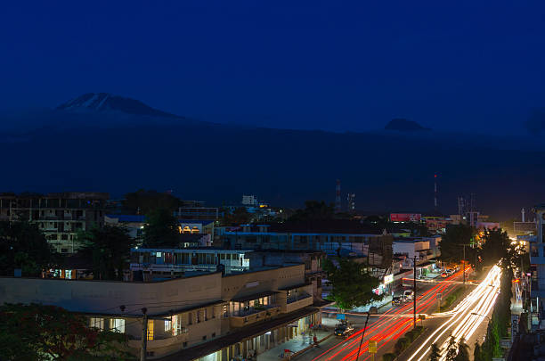 View over Moshi at night with Mount Kilimanjaro and Mawenzi Moshi, Tanzania is the town most climbers will stay before they start their journey to climb Kilimanjaro. Moshi is located at an elevation of about 800 m AMSL and Kilimanjaro in the back, with its 5895 m AMSL, is the highest mountain in Africa. mawenzi stock pictures, royalty-free photos & images