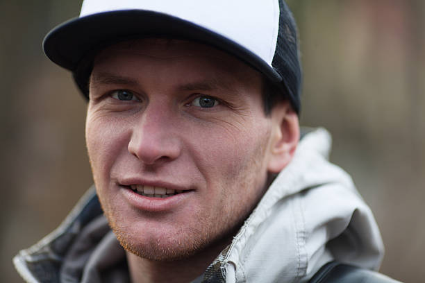 Close up of mans face wearing trucker hat and coat  stock photo