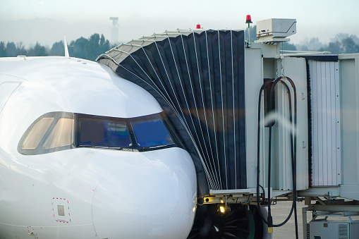 Close-up view of a white airplane connected to the jet bridge at the airport.