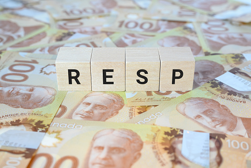 RESP (Registered Education Savings Plan) on wooden blocks and Canadian 100 dollar bills.