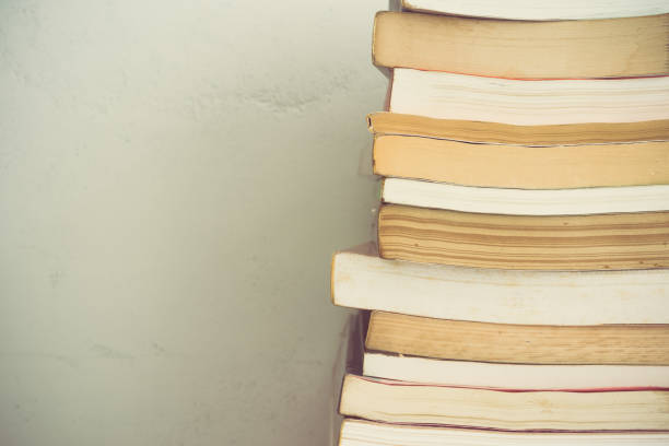 istock Stack of many old books on shelf in book store or library room with white wall background. 1619678197