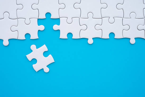istock Unfinished white jigsaw puzzle on blue background with copy space. 1619680276