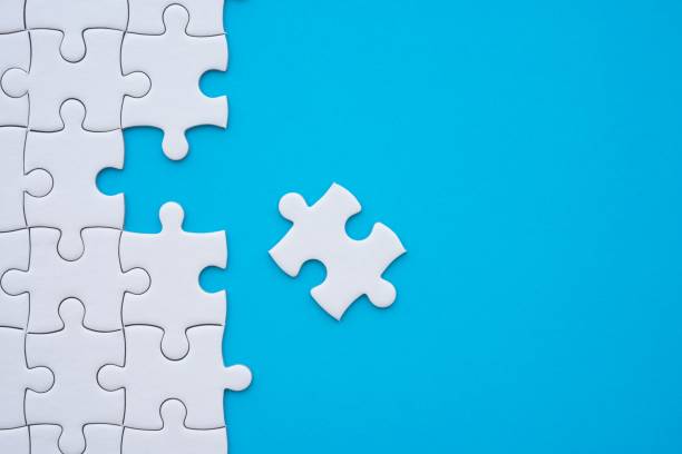 istock Unfinished white jigsaw puzzle on blue background with copy space. 1619680278