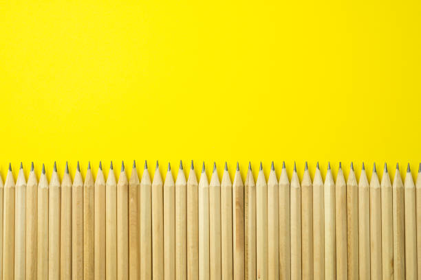 istock Simple pencils in a row on yellow background with copy space. 1619680789