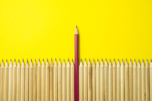 istock Leader red pencil higher than other simple pencils on yellow background. 1619680790