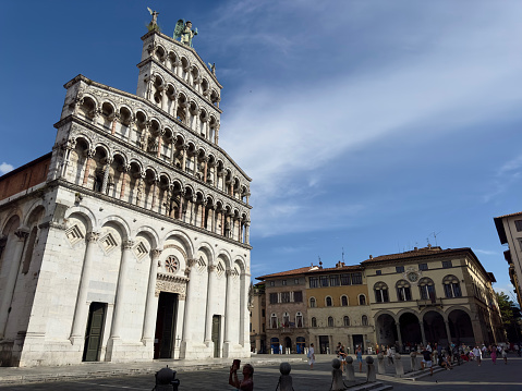 Full shot of the front/facade of the Chiesa di San Michele in Foro cathedral and city buildings in Lucca, Italy