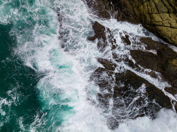istock Waves crashing on seashore rocks,Top view sea surface waves background 1619695243