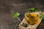 Green tea. Hot tea in a cup with mint and dry tea leaves on a dark background.