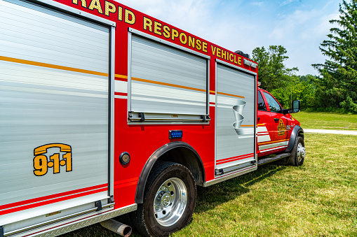 A firefighter in protective clothing and a helmet sits in a cargo rescue vehicle and talks on the radio