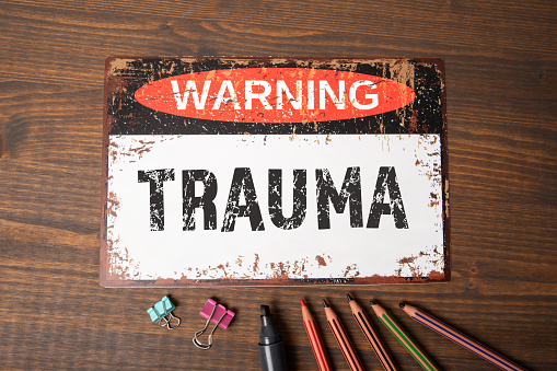 TRAUMA. Warning sign with text on wood texture background.