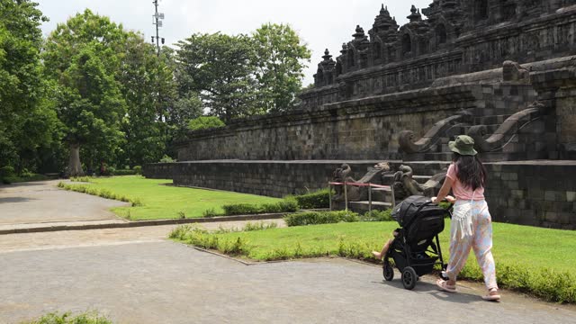 asian Chinese woman with her son walking on the grass with Borobudur temple in the background
