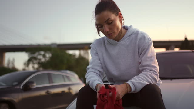 Tired and sweaty female boxer sitting on car and rest