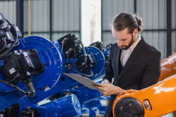 istock Man manager take note report on clipboard information checking inspection quality robotic arms for in industrial plants. management electronics development in factory. 1619822050