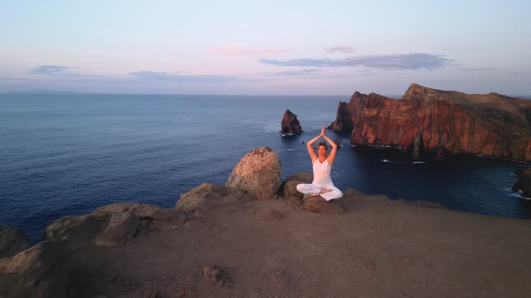 Athletic woman doing Yoga exercises on a cliff above the sea.