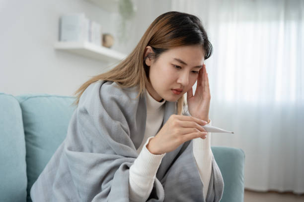 young asian woman having high fever while checking body temperature, female sneezing and runny nose with seasonal influenza, allergic, digital thermometer, virus, coronavirus, illness, respiratory - physical injury backache occupation working imagens e fotografias de stock