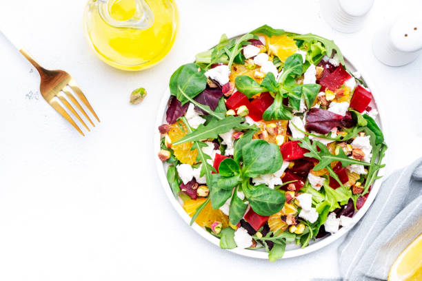 istock Beetroot and white cheese salad with arugula, lettuce,  orange and pistachios on white table. Fresh useful dish for healthy eating 1619854668