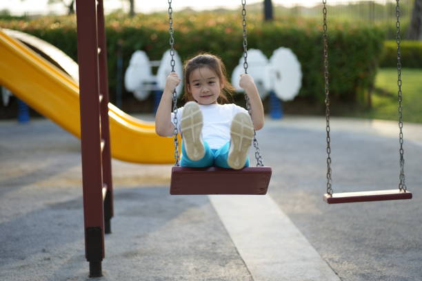 istock Little girl smiling while playing on a swing set in playground joyfully 1619915751