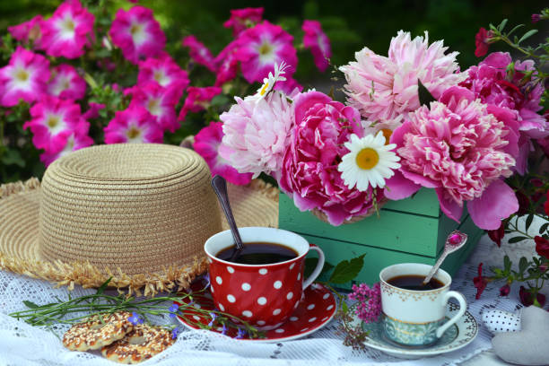 istock Beautiful still life with peony flowers bunch, tea cup and hat on the table. Romantic greeting card for birthday, Valentines, Mothers Day concept. Summer background with vintage objects 1619966165