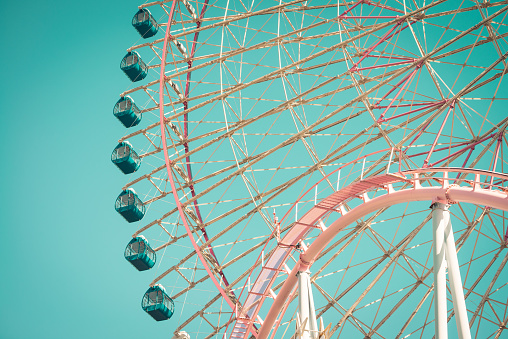 Pink pastel looping roller coaster and ferris wheel background on blue sky sunny day retro tone. Enjoy travel holiday concept.