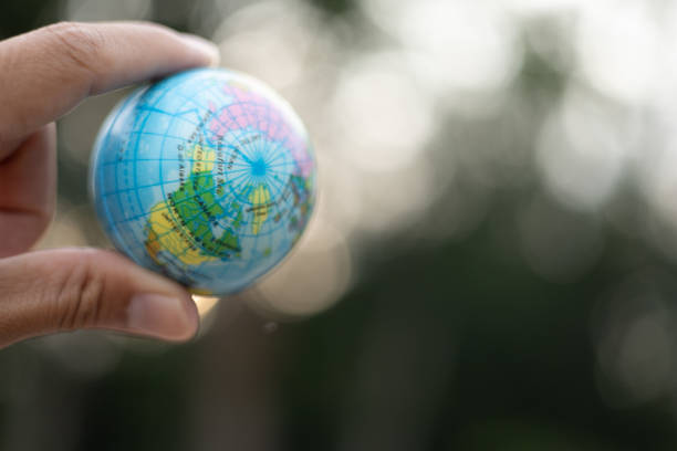 Male hand holding ball playing outdoor, blue sky, round globe, bokeh street