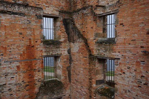 four windows with bars in red brick wall in old jail or penitentiary, in popular tourist destination Port Arthur Historic Site, Tasmania, Australia