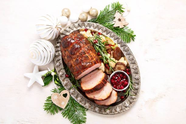 istock Roasted sliced Christmas ham on plate with vegetables, festive decoration. 1620040533