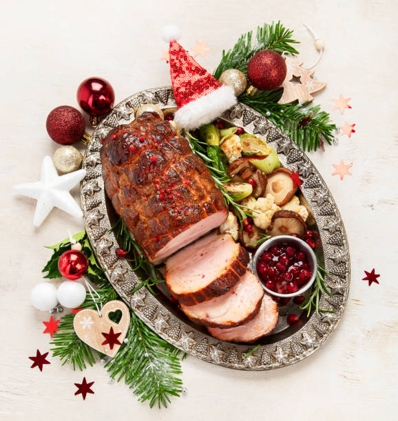 istock Roasted sliced Christmas ham on plate with vegetables, festive decoration. 1620050503