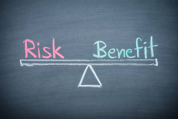 istock Text word risk and benefit balance on seesaw drawing writing on chalkboard or blackboard background. 1620056324