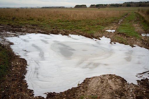 A partially melted ice puddle in a field