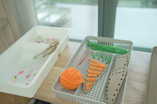 A Montessori classroom set-up, threading activity, carrot shaped sewing cards, practical life skill, preliminary exercises in Montessori education school