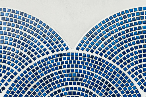 Detail of wall surface texture white blue mosaic ceramic tiles arch geometric ornaments pattern background. Outdoor architecture design decoration inspire from ocean.