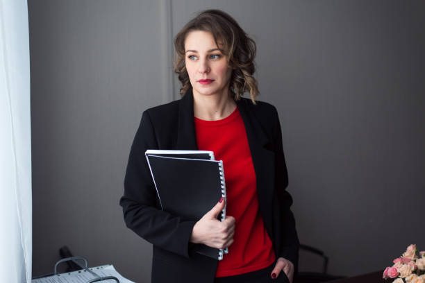 istock Young business woman or manager standing at workplace with folders 1620111039
