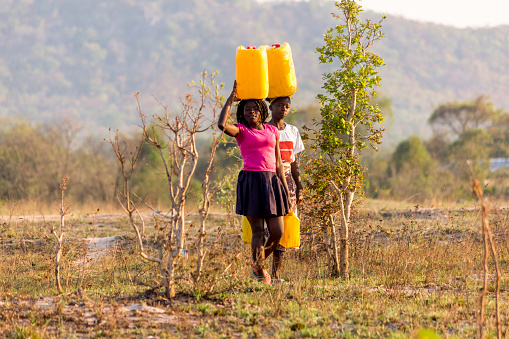 Two girls carrying gallons of Water on their heads in a water-scarce region