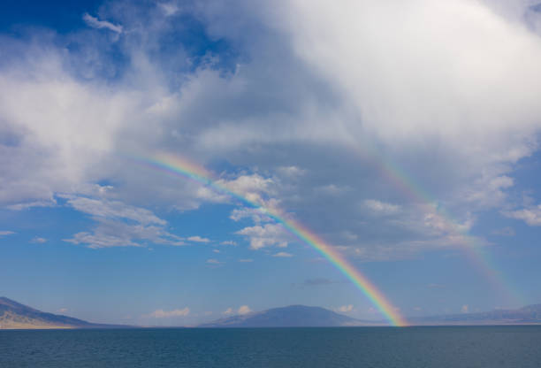 After the Rain, Two Parallel Rainbows Appear Over Sary-Chelek Lake, Creating a Breathtaking Scene of Blue Sky, White Clouds, Mountains, Blue Waters, and Two Beautiful Rainbows