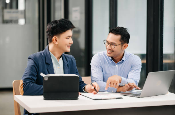 istock Two Asian business workers talking on the smartphone, tablet and using laptop at the office. 1620194792