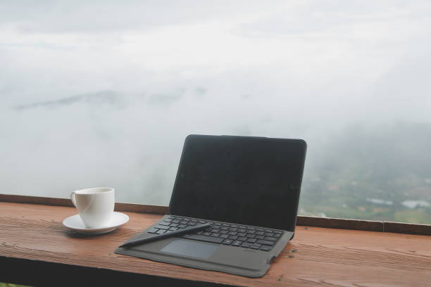 istock Computer Monitor, Keyboard, coffee cup and Mouse with Blank is on the work table at the sky mountain river and trees front view background. 1620199759