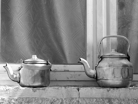 Copper teapots standing to concrete sill, kettles on street shop window before glass, teapot consisting of copper kettles with handle, spout for draining liquid coffee, copper kettles is iron teapots