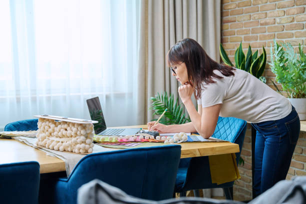 istock Mature woman interior designer working at her desk with fabric samples, laptop 1620259964